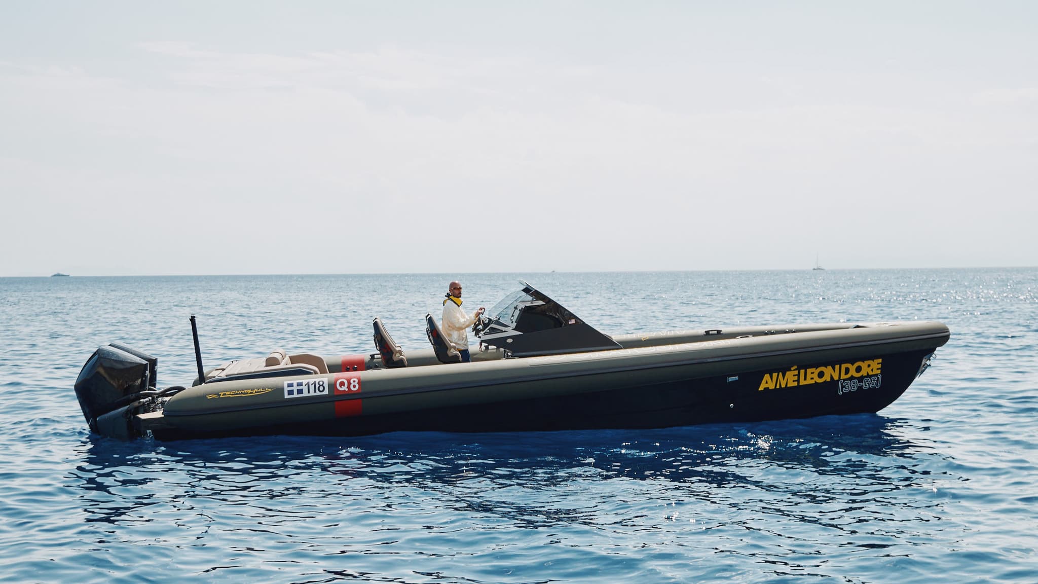 Aimé Leon Dore and Technohull speedboat moving at high speed on open water with a helicopter