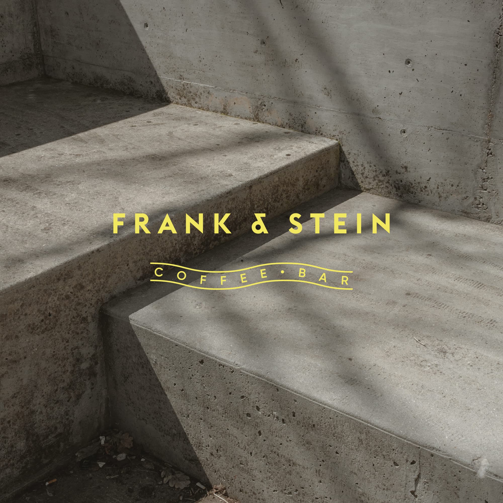 Frank & Stein café counter with signage, muted materials, and staff preparing drinks